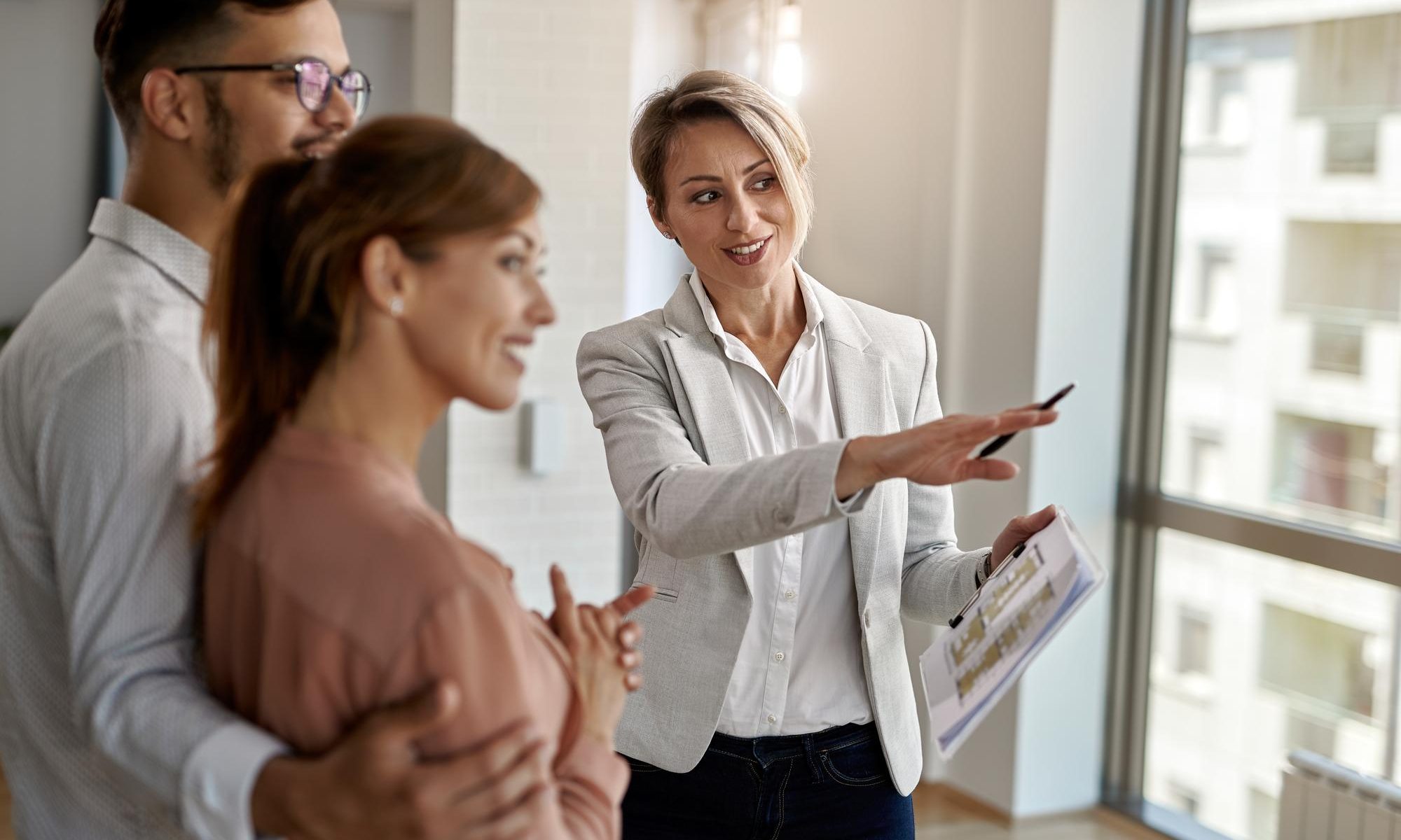 Smiling real estate agent talking with couple interested buying new home