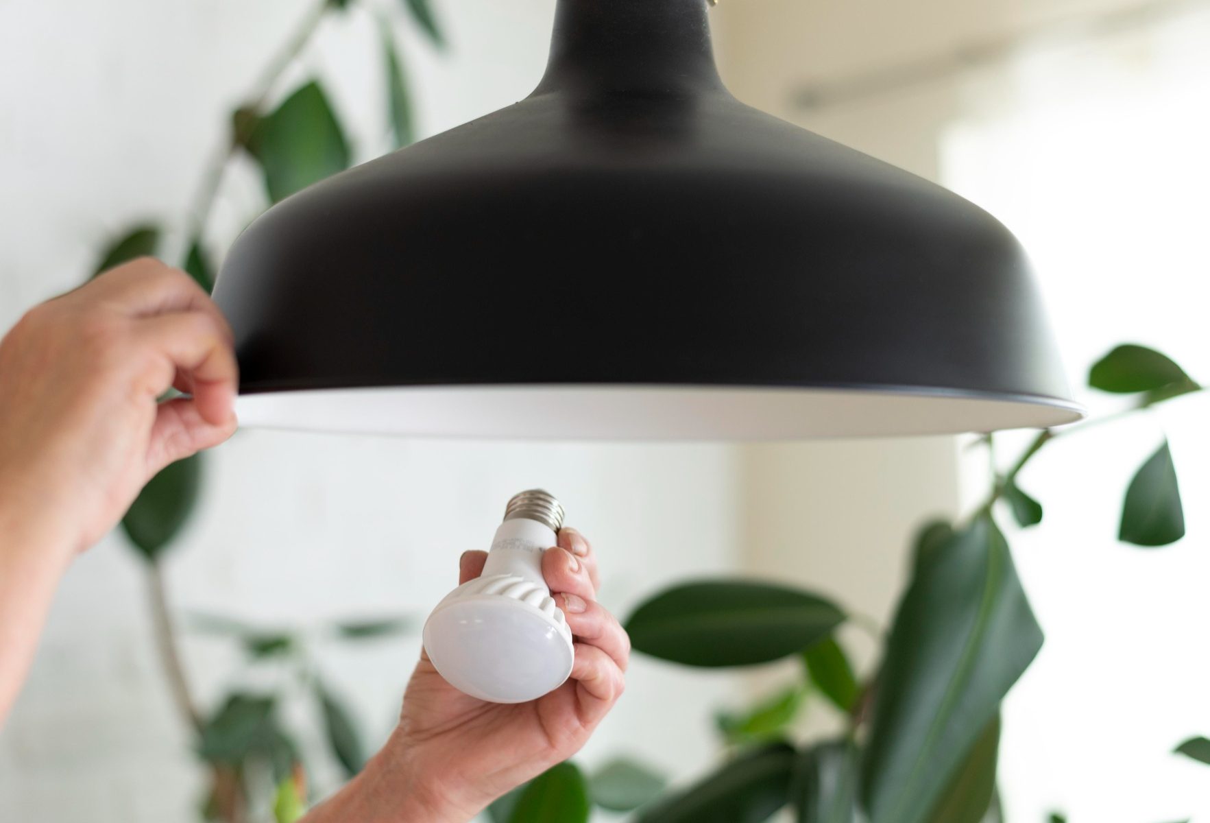 Close up of hands changing lightbulb to a LED