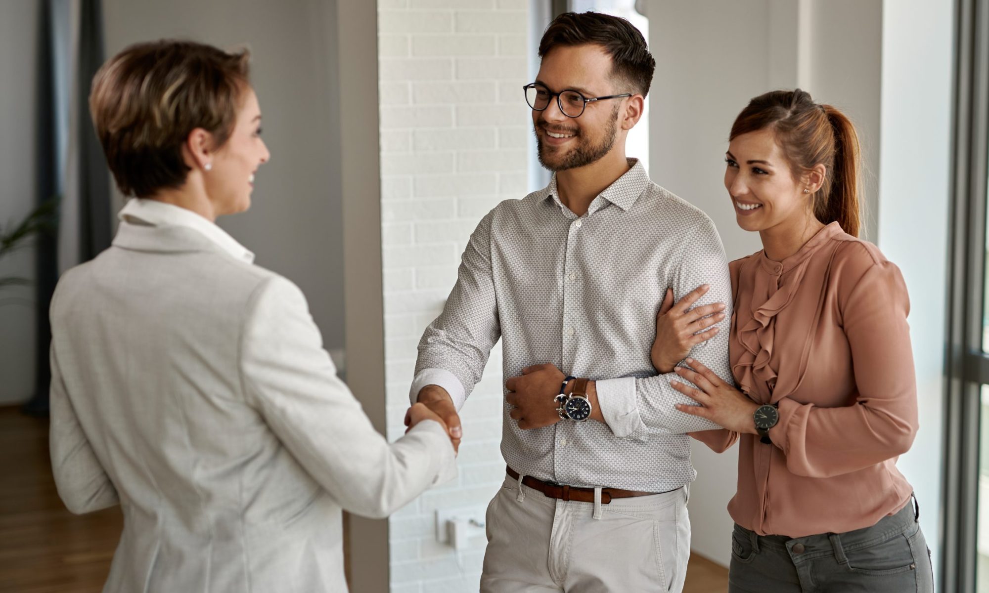 Young happy couple shaking hands with real estate agent to show that a property manager should build strong relationships with your tenant