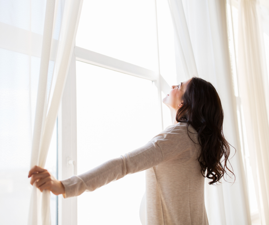 Woman opens window, drawing in fresh air and natural light