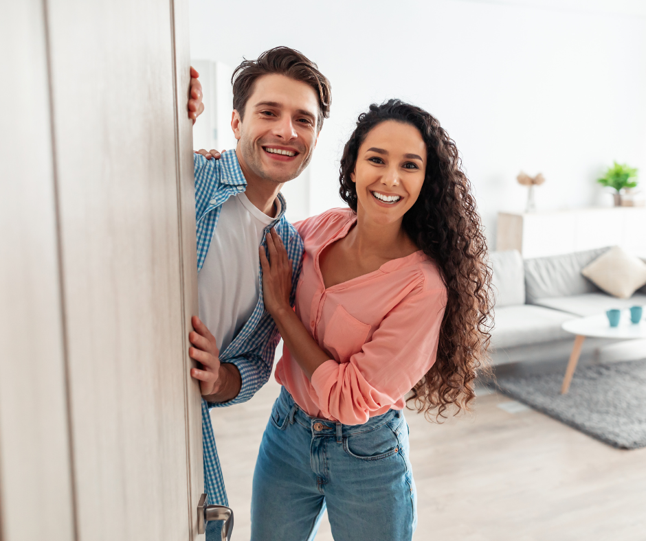 Young couple opening the door of their new home after making a winning offer